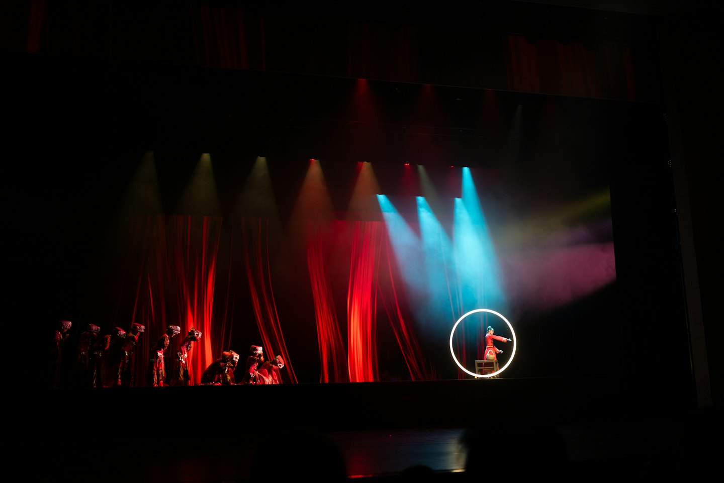 Artisti in costume tradizionale su un palco poco illuminato.