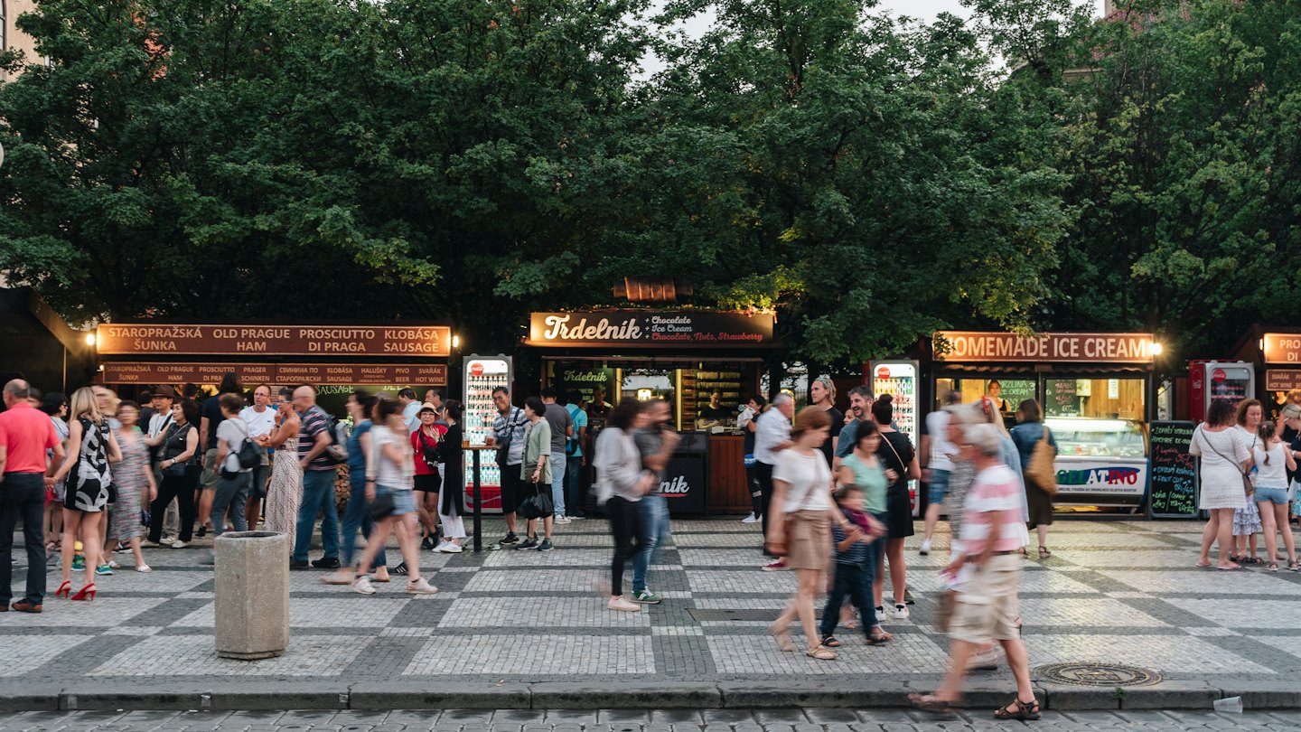 Persone che curiosano tra le bancarelle di cibo in un vivace mercato all'aperto di notte.